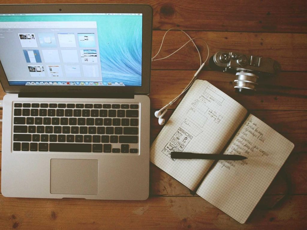 Het bureau waar Tom zijn portfolio samenstelde: laptop, schetsen en camera