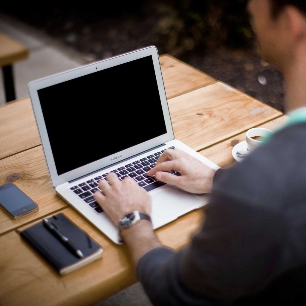 Iemand programmeert op een laptop aan een houten tafel
